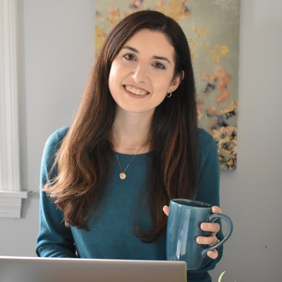 Bethany Barba, smiling and holding a mug at her desk